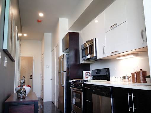 Modern galley kitchen with white and dark cabinetry at 68 Beale Apartments, Quincy
